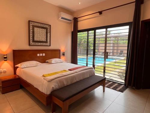 a bedroom with a bed and a large window with a pool at Villa Tiana - 3Bedroom Villa with private pool. in Kribi