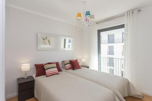ein weißes Schlafzimmer mit einem Bett und einem Fenster in der Unterkunft Bairrus Lisbon Apartments - Mello in Lissabon