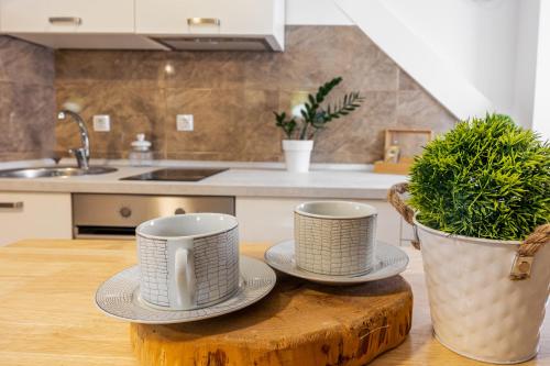 dos tazas y platillos en una mesa de madera en una cocina en Stone apartment in Center, en Kaštela