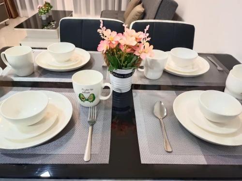 a table with white plates and a vase of flowers at Medini Elysia Park , 3 min to Legoland, Netflix By Hint Homestay in Nusajaya
