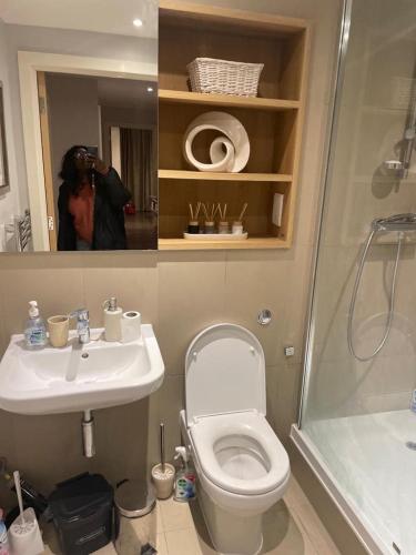 a person taking a picture of a bathroom with a toilet and shower at Luxurious Furnished Property in Stanmore