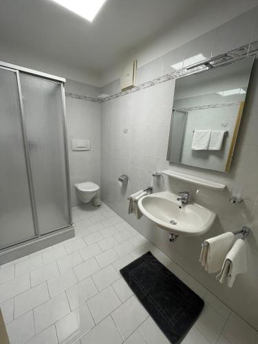 ein weißes Badezimmer mit Dusche und Waschbecken in der Unterkunft Blummerhof in Algund