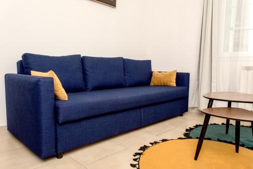 a blue couch in a living room with two tables at Le Brivetain ✩ Hypercentre ✩ Parking gratuit in Pontchâteau