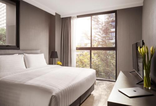 a bedroom with a large bed and a window at Walton Suites Sukhumvit in Bangkok