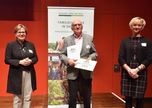 a man and two women standing in front of a banner at Hotel Regenbogenhaus in Freiberg
