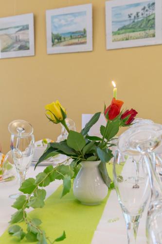 a table with a white vase with roses in it at Hotel Regenbogenhaus in Freiberg