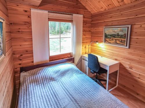 1 dormitorio con cama, escritorio y ventana en Peaceful log cabin in the country en Nurmijärvi