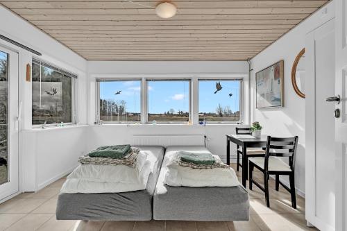 a bedroom with a bed and a table and windows at Guldbergs Guesthouse in Kerteminde