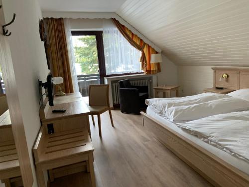 een slaapkamer met een bed, een bureau en een raam bij Ferienwohnung Wiesenblick mit Terrasse im Landhaus Fischer in Sankt Andreasberg