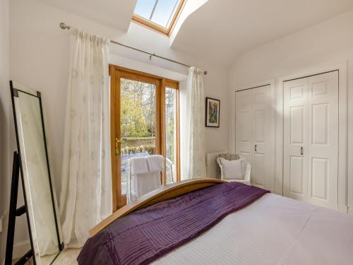 a bedroom with a large bed and a window at Appletree Cottage in Kirkton of Tealing