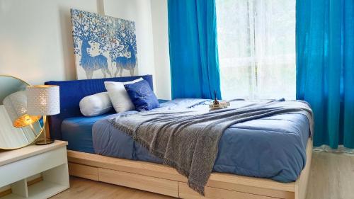 a blue bed with blue curtains and a window at Elio Del Ray in Bangkok