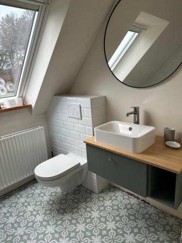 La salle de bains est pourvue d'un lavabo, de toilettes et d'un miroir. dans l'établissement Le Cottage, à Lasne