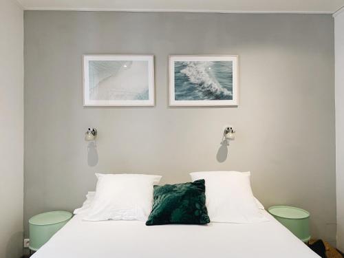 una camera con un letto bianco con due immagini sul muro di Outsite Coliving Biarritz a Biarritz