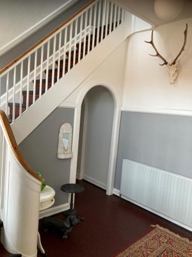 a hallway with a staircase with a stool and a toilet at Store Sand in Vemb