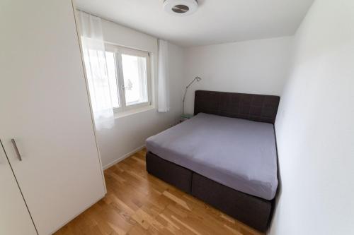 a small bedroom with a bed and a window at Studio CHic in Niederweningen