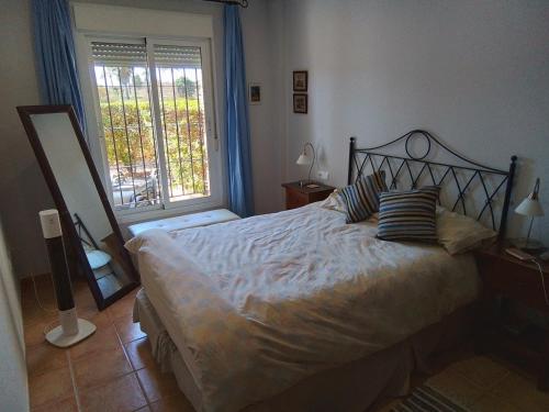 een slaapkamer met een bed, een spiegel en een raam bij THALLASA APARTMENT VERA PLAYA in Playas de Vera