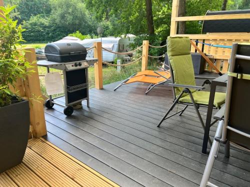 a patio with a grill and chairs on a deck at Tiny House Carlos in Stuer