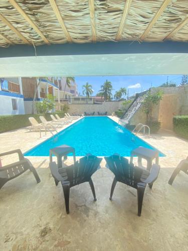 a table and chairs in front of a swimming pool at Hotel Checo Sosúa in Sosúa