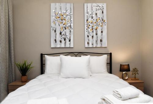 una camera da letto con un letto bianco e due dipinti alle pareti di Katerina's Place a Argos
