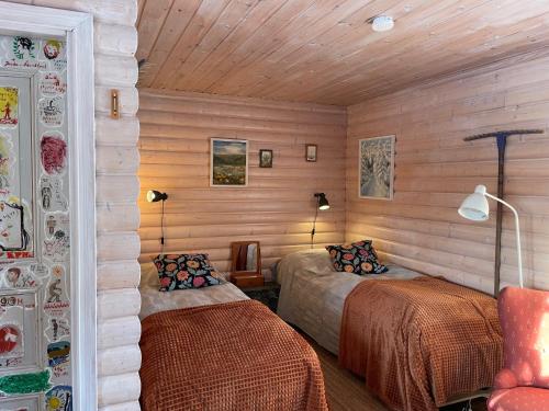 2 Betten in einem Zimmer mit Holzwänden in der Unterkunft Ateljéstugan med magisk utsikt in Nordingrå