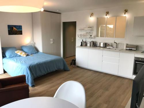 une chambre avec un lit bleu et une cuisine dans l'établissement Calme et Vue - Plage 150m - Quartier Lajarrige -, à La Baule