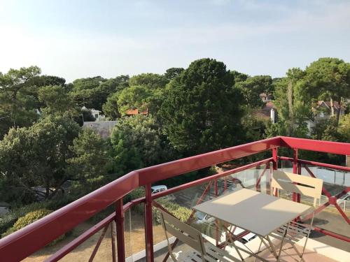 un balcon rouge avec une table et des chaises blanches dans l'établissement Calme et Vue - Plage 150m - Quartier Lajarrige -, à La Baule