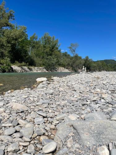 une rivière rocheuse avec des arbres et un ciel bleu dans l'établissement Logement atypique tout en pierre, à La Coucourde