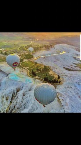 two hot air balloons are flying over a river at OzenTurku Hotel in Pamukkale