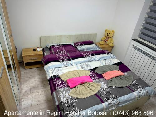 um quarto com uma cama com almofadas e um ursinho de peluche em Apartament Uvertura Mall/Lidl cu parcare gratuita em Botoşani
