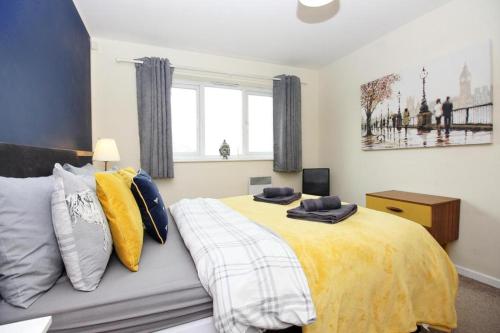 a bedroom with a large bed with yellow blankets and pillows at Hidden Gem of Newark - Sleeps 6 in Ollerton