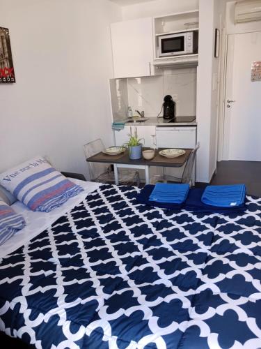 1 dormitorio con edredón azul y blanco en una cama en studio à 2 mn à pied de la plage en Niza