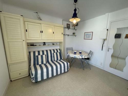 - une chambre avec un canapé rayé et une table dans l'établissement Studio agréable à 20m de la plage - 2 personnes - FR-1-224C-83, à Notre-Dame-de-Monts
