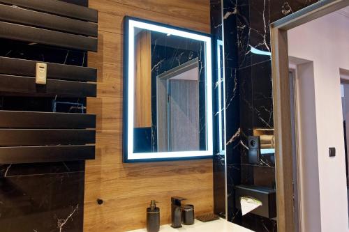 W łazience znajduje się lustro i umywalka. w obiekcie Apartament e-Space w mieście Rzeszów