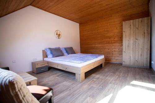 a bedroom with a bed and a wooden wall at TINA Apartments in Černá v Pošumaví
