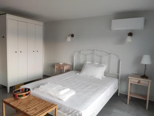1 dormitorio con cama blanca y mesa de madera en Theros - Bahia, en Elafonisos
