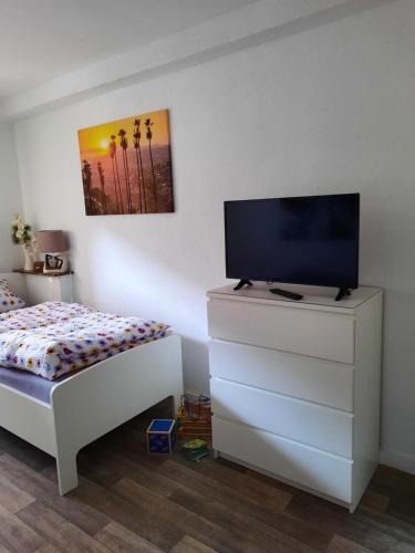 a bedroom with a bed and a tv on a dresser at Ferienwohnung am Rittershof Heusweiler in Heusweiler