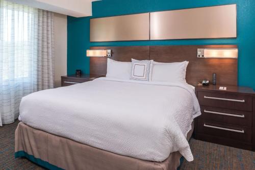 Residence Inn by Marriott Decatur في ديكاتور: غرفة نوم بسرير كبير وجدار ازرق