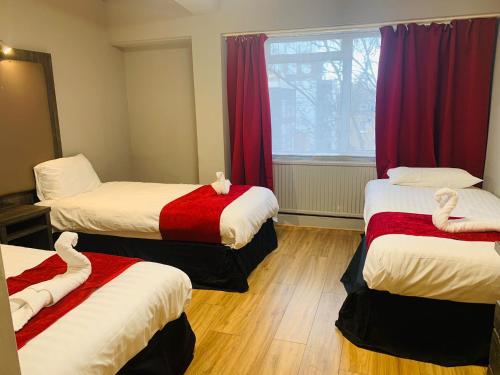 um quarto com três camas e uma janela em Hotel Lily em Londres