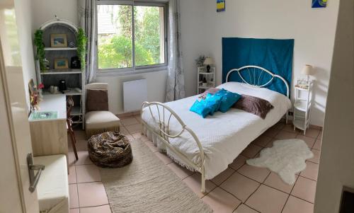 Un dormitorio con una cama con almohadas azules y una ventana en Maison Chevreuse, chambre chez l'habitant, en Magny-les-Hameaux