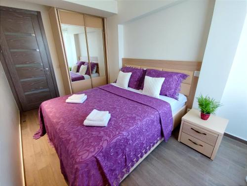 a bedroom with a purple bed with two towels on it at 2BR+living downtown Chișinău in Chişinău