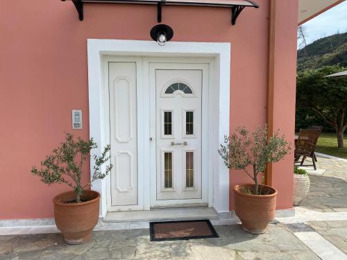 a white door on a pink house with two plants at Villa Aris in Olympia