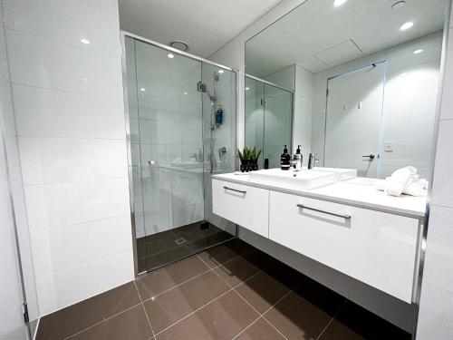 a white bathroom with a shower and a sink at Deluxe 3 Bedroom Apartment in Southbank in Melbourne