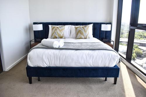 a bedroom with a large bed with a blue headboard at Deluxe 3 Bedroom Apartment in Southbank in Melbourne