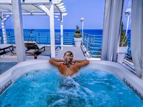 mężczyzna leżący w jacuzzi na patio w obiekcie Panorama Suites & Spa - Adults Only w mieście Stomio