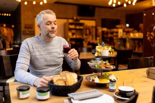 シュネーヴァーディンゲンにあるHotel Ehlersのワインを飲みながら座る男