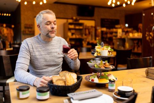 un hombre sentado en una mesa con una copa de vino en Hotel Ehlers, en Schneverdingen