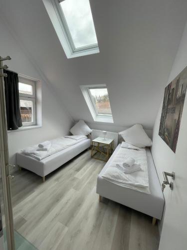 two beds in a white room with two windows at ROYAL APARTMENTS in Lunca de Sus