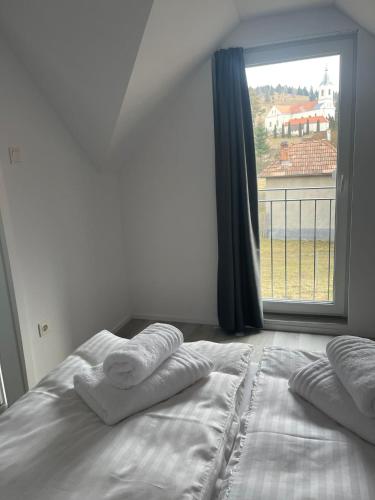 a bedroom with a bed with two pillows and a window at ROYAL APARTMENTS in Lunca de Sus