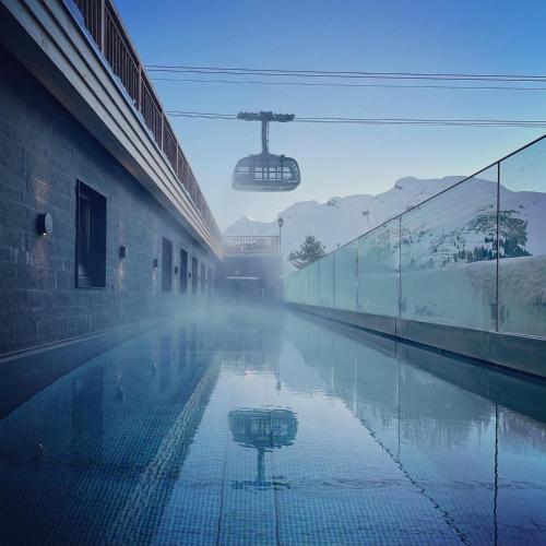 a building with a reflection in a pool of water at Hotel Petersboden in Lech am Arlberg