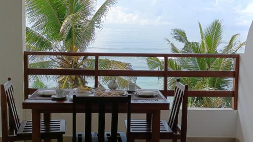 a table and chairs on a balcony with a view of the ocean at La Polena in Matara